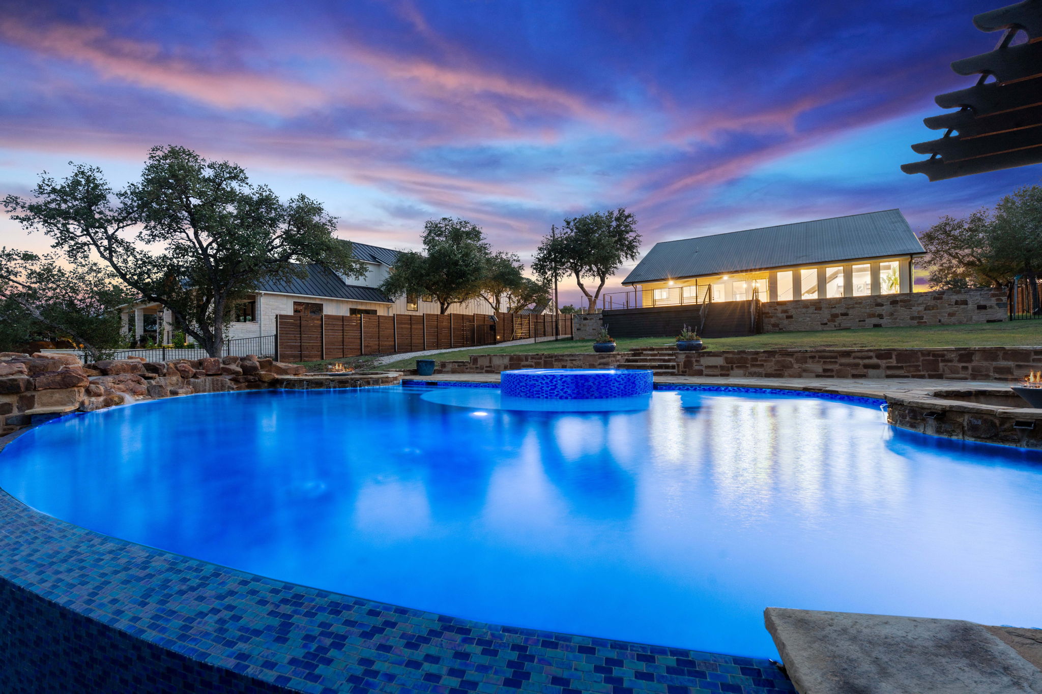 1325 Likeness Road Spicewood, TX 78669 - Photo 4 of 40 Pool at dusk featuring a pool with connected hot tub, a fenced backyard, and a patio area
