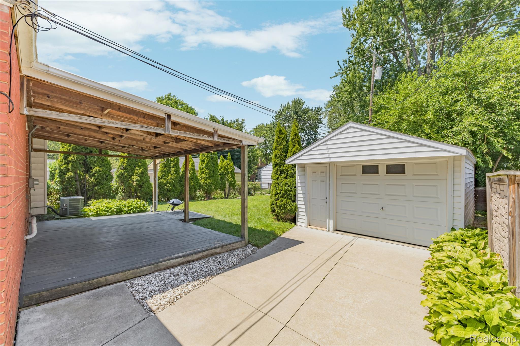 26508 Five Mile Road Redford, MI 48239 - Photo 34 of 41 Detached garage with white siding and a single overhead door, complemented by a covered patio with a wood-finish deck