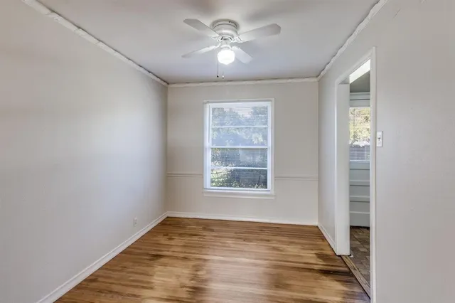 a view of an empty room with a window and wooden floor