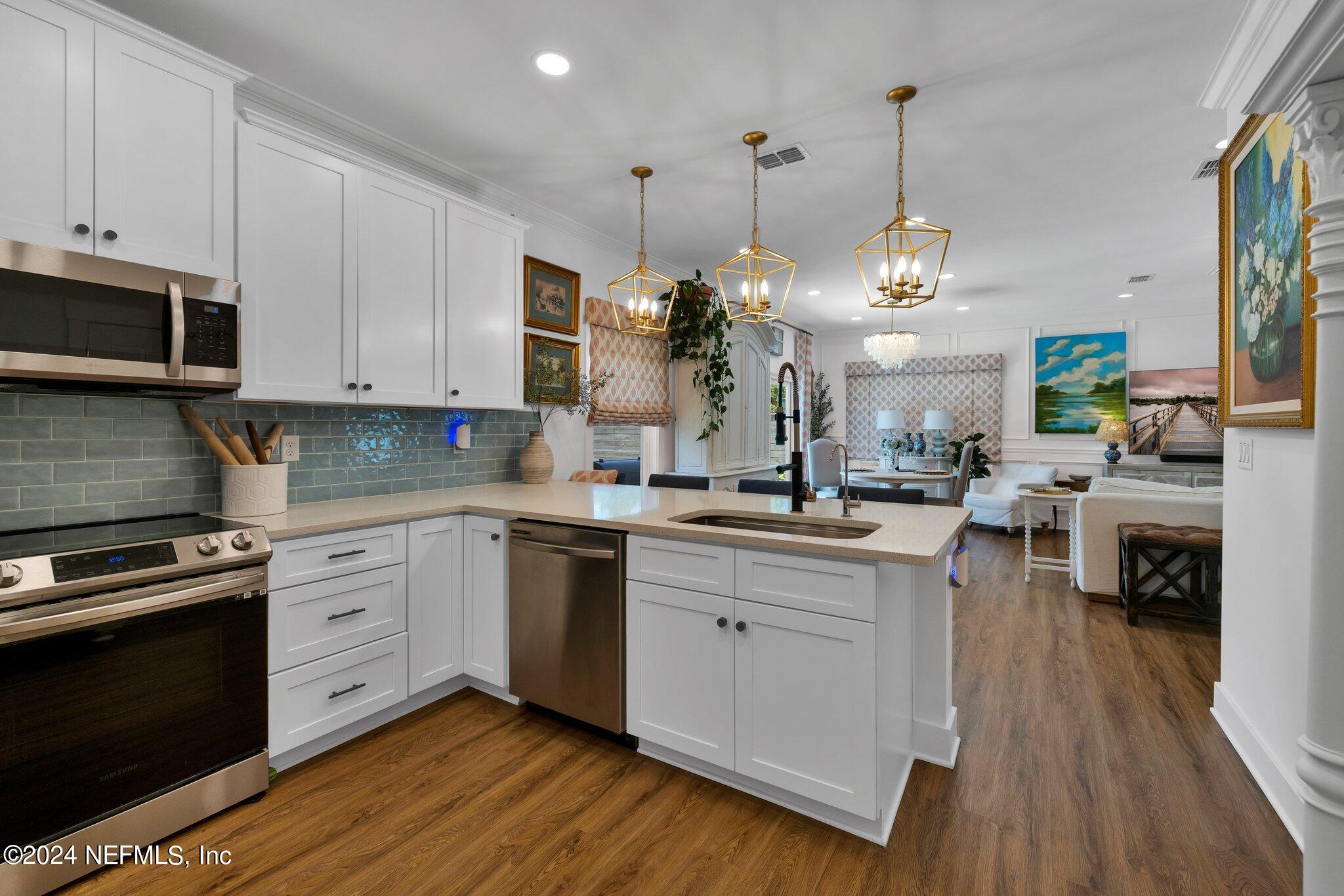 6825 A Ave Street St. Augustine, FL 32080 - Photo 46 of 53 a kitchen with white cabinets stainless steel appliances and wooden floor