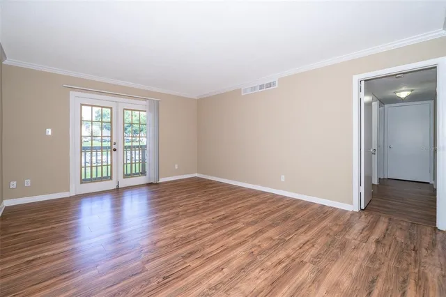 a view of an empty room with wooden floor and a window