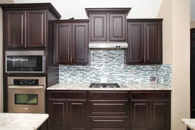 a kitchen with granite countertop wooden cabinets and a stove top oven