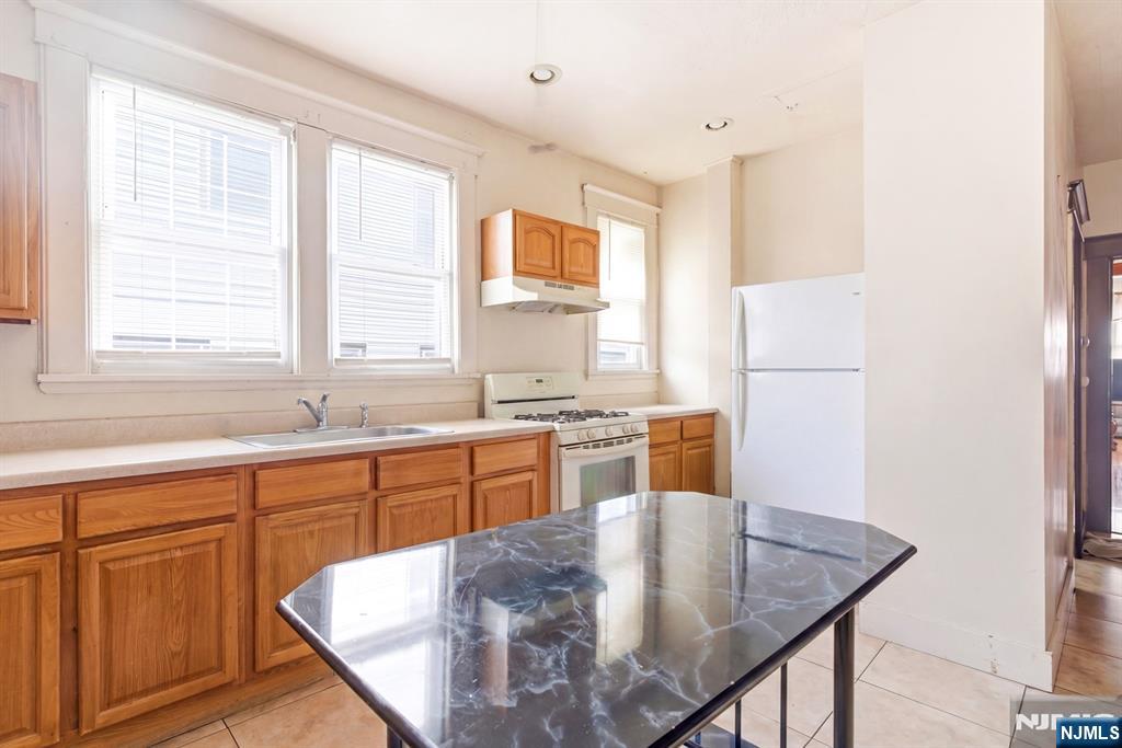 73-75 Knickerbocker Avenue Paterson, NJ 07503 - Photo 18 of 27 a kitchen with stainless steel appliances granite countertop a sink a stove a dining table and chairs