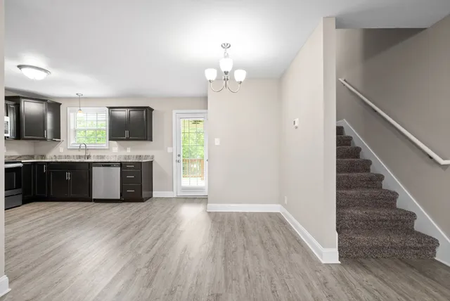 a large kitchen with granite countertop a stove top oven a sink dishwasher a dining table and chairs with wooden floor