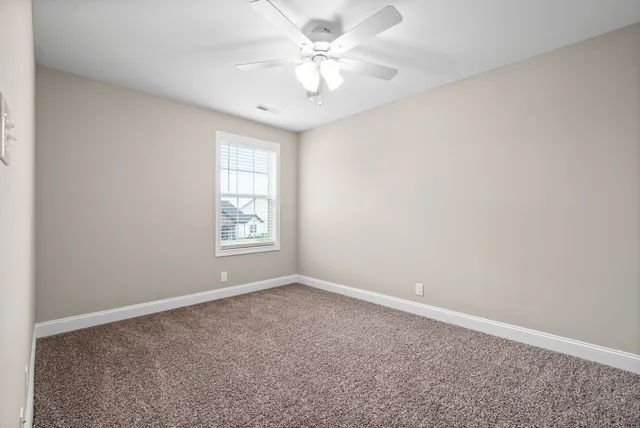 an empty room with windows and ceiling fan