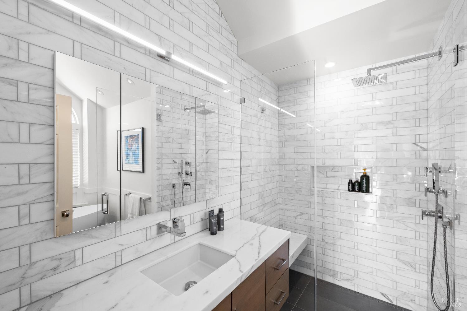 26 Mooring Road San Rafael, CA 94901 - Photo 44 of 60 The remodeled spa-like primary bath includes a custom vanity, custom tile walk-in shower with glass surround, bidet toilet and soaking tub.