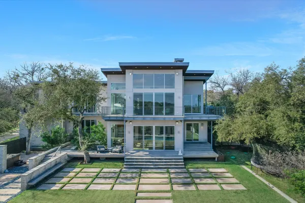 an aerial view of a house with outdoor space and trees all around