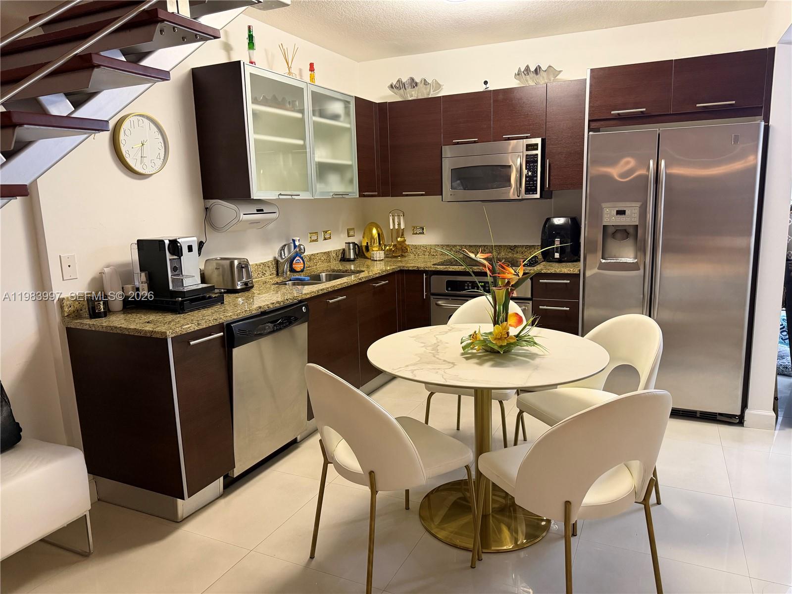 41 Southeast 5th Street, Unit 1106 Miami, FL 33131 - Photo 7 of 10 a kitchen with stainless steel appliances granite countertop a sink a microwave a refrigerator and chairs