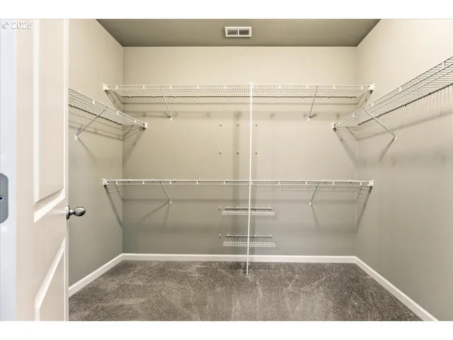 a view of walk in closet with clothes and racks on the wall