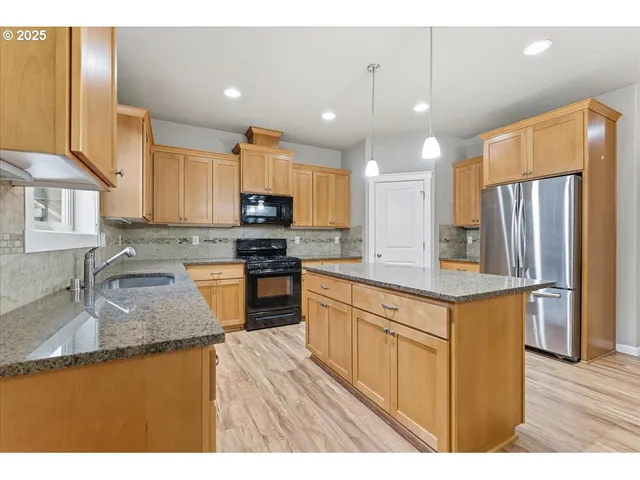 a kitchen with stainless steel appliances granite countertop a sink stove and refrigerator