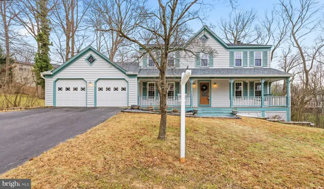 a view of white house with a large tree and plants