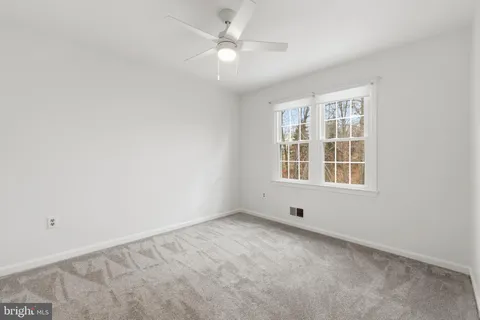 an empty room with windows and ceiling fan