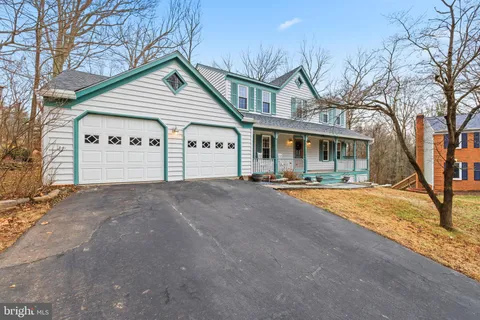 a view of a white house with a large tree and wooden fence