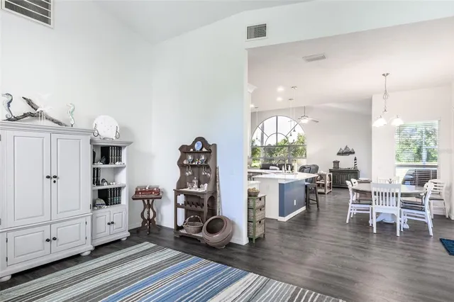 a kitchen with stainless steel appliances kitchen island granite countertop a dining table chairs sink refrigerator and cabinets