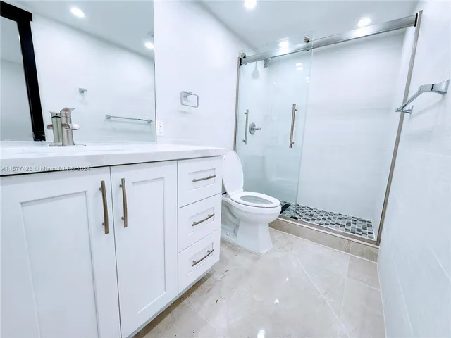a spacious bathroom with a granite countertop sink mirror vanity and toilet