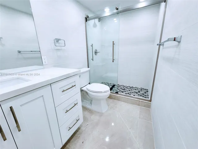 a bathroom with a granite countertop sink a toilet a mirror and shower