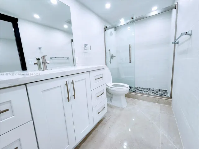 a bathroom with a sink a toilet a mirror and shower