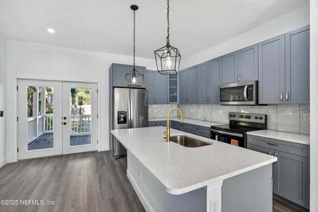 a kitchen with stainless steel appliances wooden floor sink stove and refrigerator