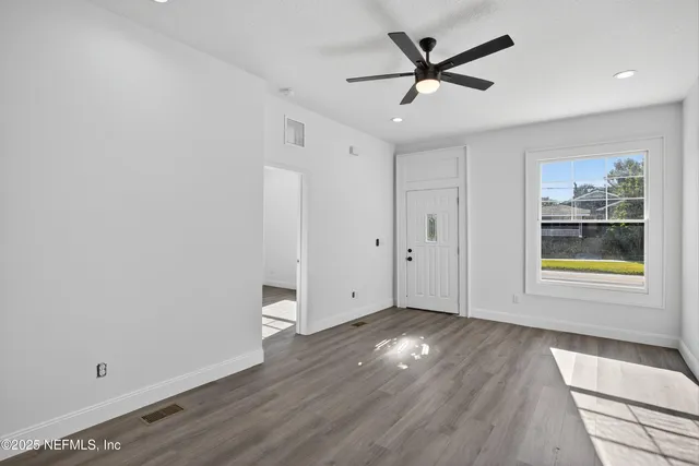a view of an empty room with window and wooden floor