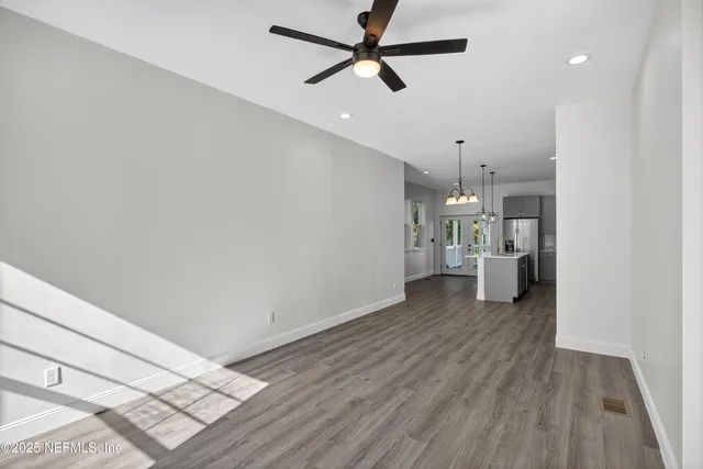 a view of a room with wooden floor and a ceiling fan