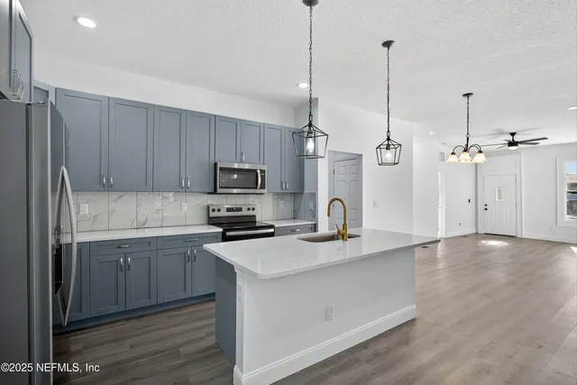 a kitchen with stainless steel appliances granite countertop a sink a refrigerator a stove and a wooden floors