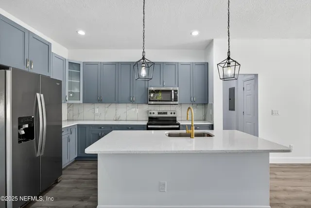a kitchen with kitchen island a counter top space stainless steel appliances and cabinets