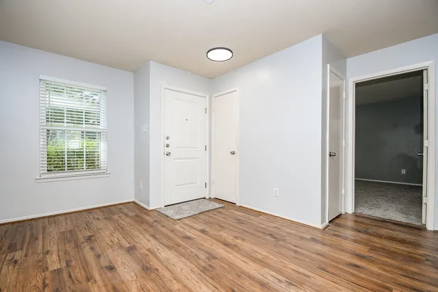 an empty room with wooden floor and windows