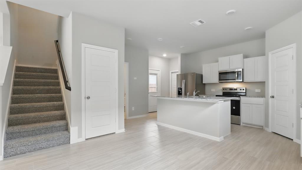 3149 Maple Orch Lane Fort Worth, TX 76140 - Photo 9 of 39 a kitchen with white cabinets and stainless steel appliances