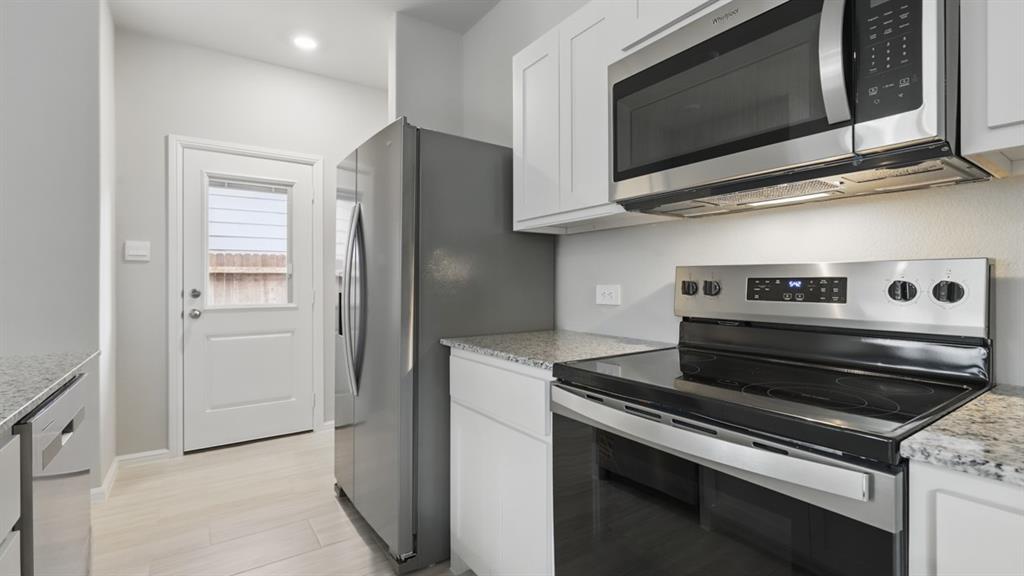3149 Maple Orch Lane Fort Worth, TX 76140 - Photo 4 of 39 a kitchen with stainless steel appliances granite countertop a stove microwave and refrigerator