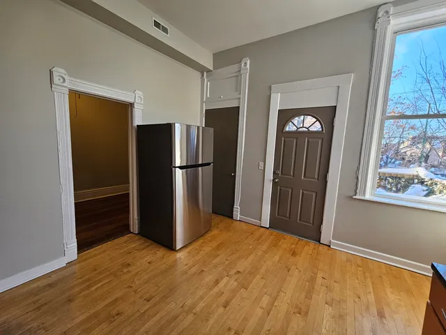 a view of a kitchen with wooden floor refrigerator and a window