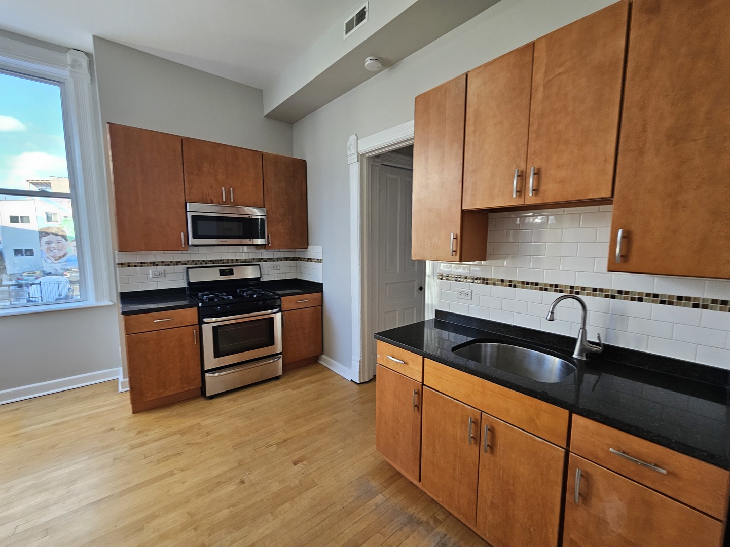 2000 South Ashland Avenue, Unit 1 Chicago, IL 60608 - Photo 10 of 23 a kitchen with stainless steel appliances granite countertop a sink a stove a refrigerator cabinets and a window