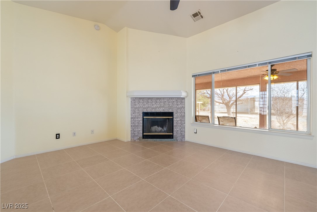 3581 Ranger Way Pahrump, NV 89048 - Photo 26 of 57 living room with a ceiling fan, visible vents, a fireplace, and light tile patterned floors