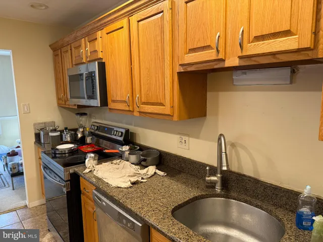 a kitchen with granite countertop a sink a stove and cabinets