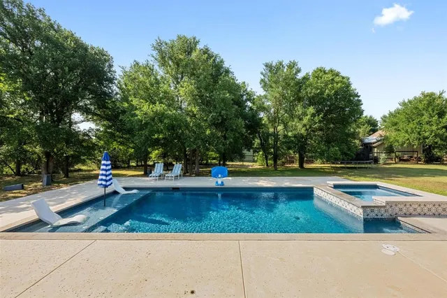 a view of a swimming pool with a bench and trees around