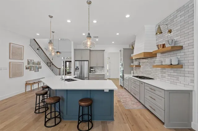 a kitchen with kitchen island a dining table chairs wooden floor and appliances