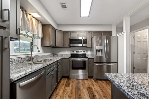 a kitchen with granite countertop stainless steel appliances and wooden cabinets