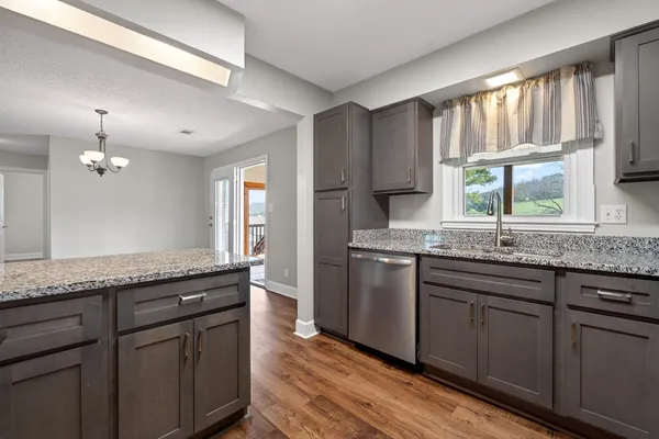 a kitchen with granite countertop wooden cabinets a sink a window and appliances