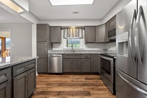 a kitchen with stainless steel appliances granite countertop a sink stove and refrigerator