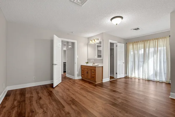 an empty room with wooden floor and windows