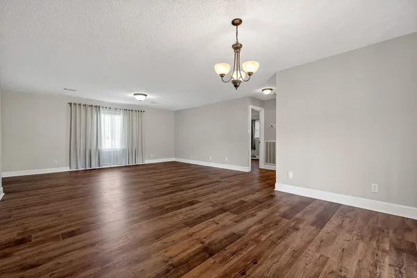a view of empty room with wooden floor and ceiling fan