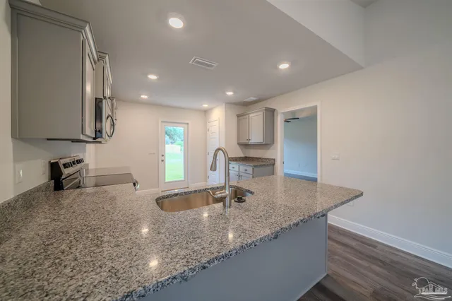 a kitchen with stainless steel appliances granite countertop a sink a stove and a refrigerator