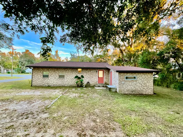 a view of a house with a yard and large tree