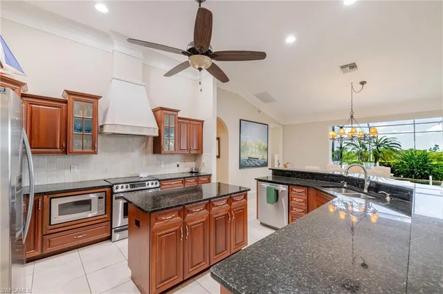 a kitchen with stainless steel appliances granite countertop a sink a stove and a wooden cabinets