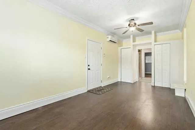 an empty room with wooden floor fan and windows