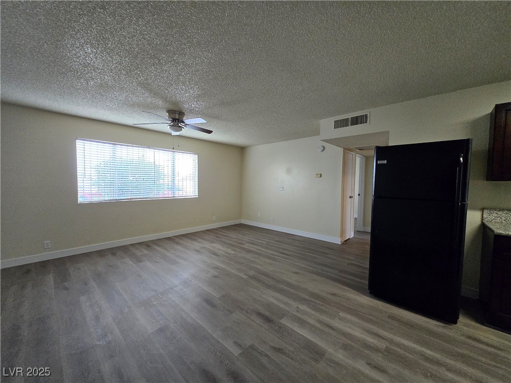 218 East Merlayne Drive, Unit 1 Henderson, NV 89011 - Photo 2 of 11 Unfurnished living room with wood finished floors, a textured ceiling, and a ceiling fan