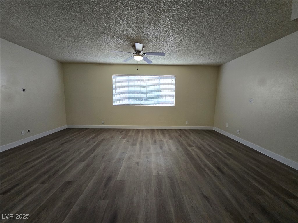 218 East Merlayne Drive, Unit 1 Henderson, NV 89011 - Photo 5 of 11 Empty room featuring a textured ceiling, dark wood-style floors, and ceiling fan
