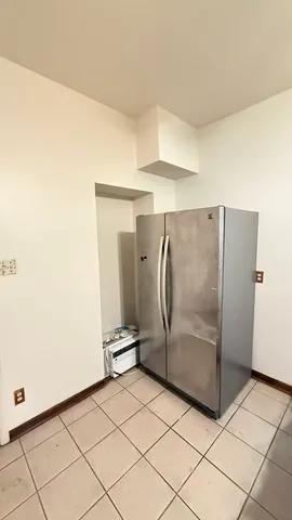 a view of a refrigerator in kitchen and an empty room