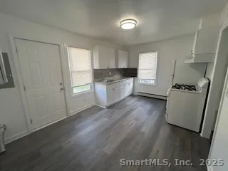 a kitchen with a refrigerator a stove top oven and wooden floor