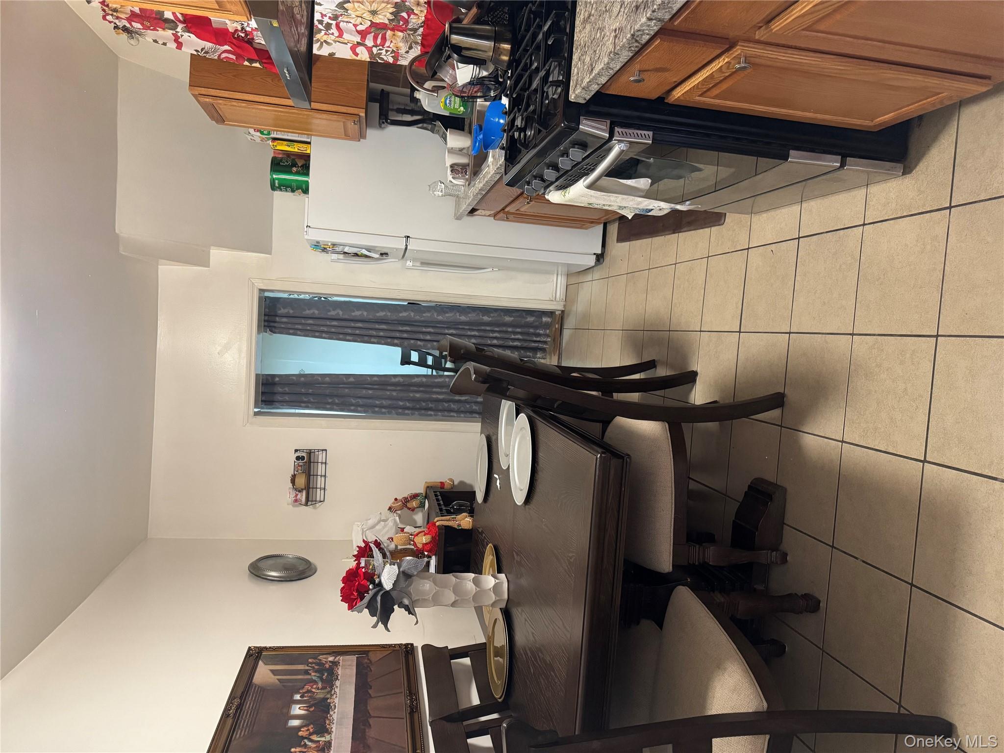 94-13 116th Street Queens, NY 11419 - Photo 16 of 34 Kitchen featuring brown cabinetry, stove, light tile patterned flooring, range hood, and light stone counters