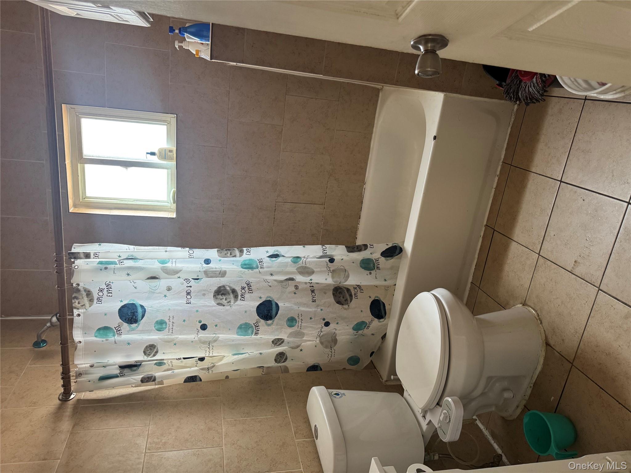 94-13 116th Street Queens, NY 11419 - Photo 26 of 34 Bathroom featuring shower / bath combo with shower curtain, tile walls, light tile patterned floors, and vanity